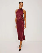 Woman wearing a burgundy satin halter top with matching satin skirt