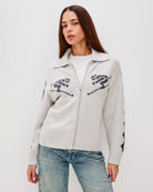 Grey zip up sweater with two skiiers on the chest in blue
