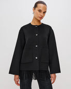 Person wearing a black jacket with fringes  on the hem