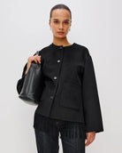 Person wearing a black jacket with fringes  on the hem