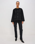 Person wearing a black jacket with fringes  on the hem