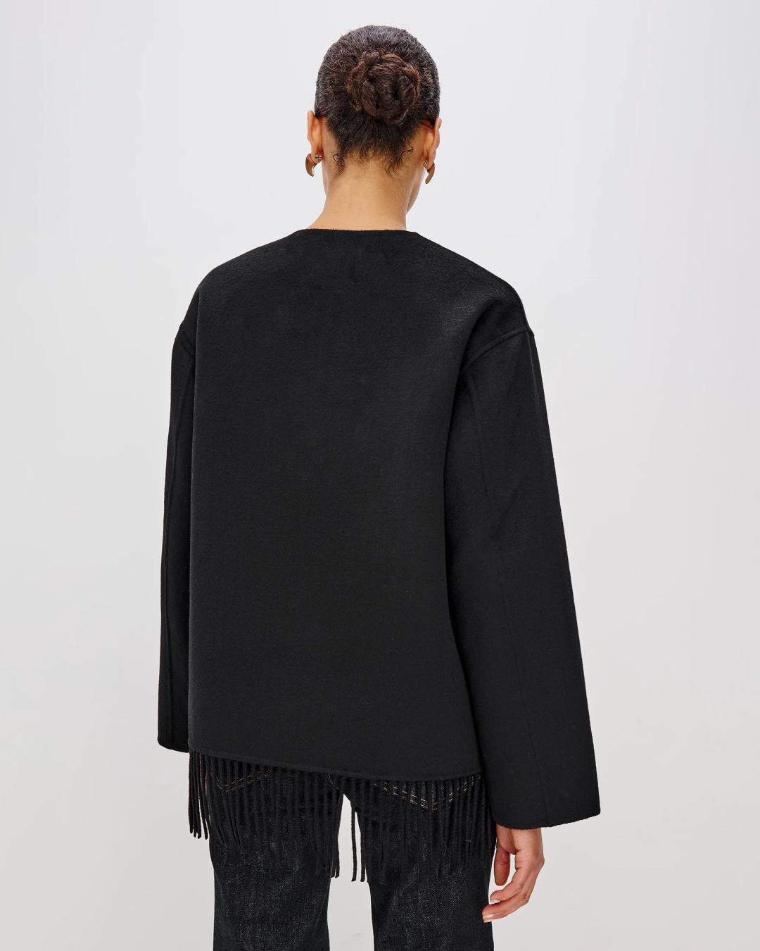 Person wearing a black jacket with fringes  on the hem