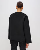 Person wearing a black jacket with fringes  on the hem