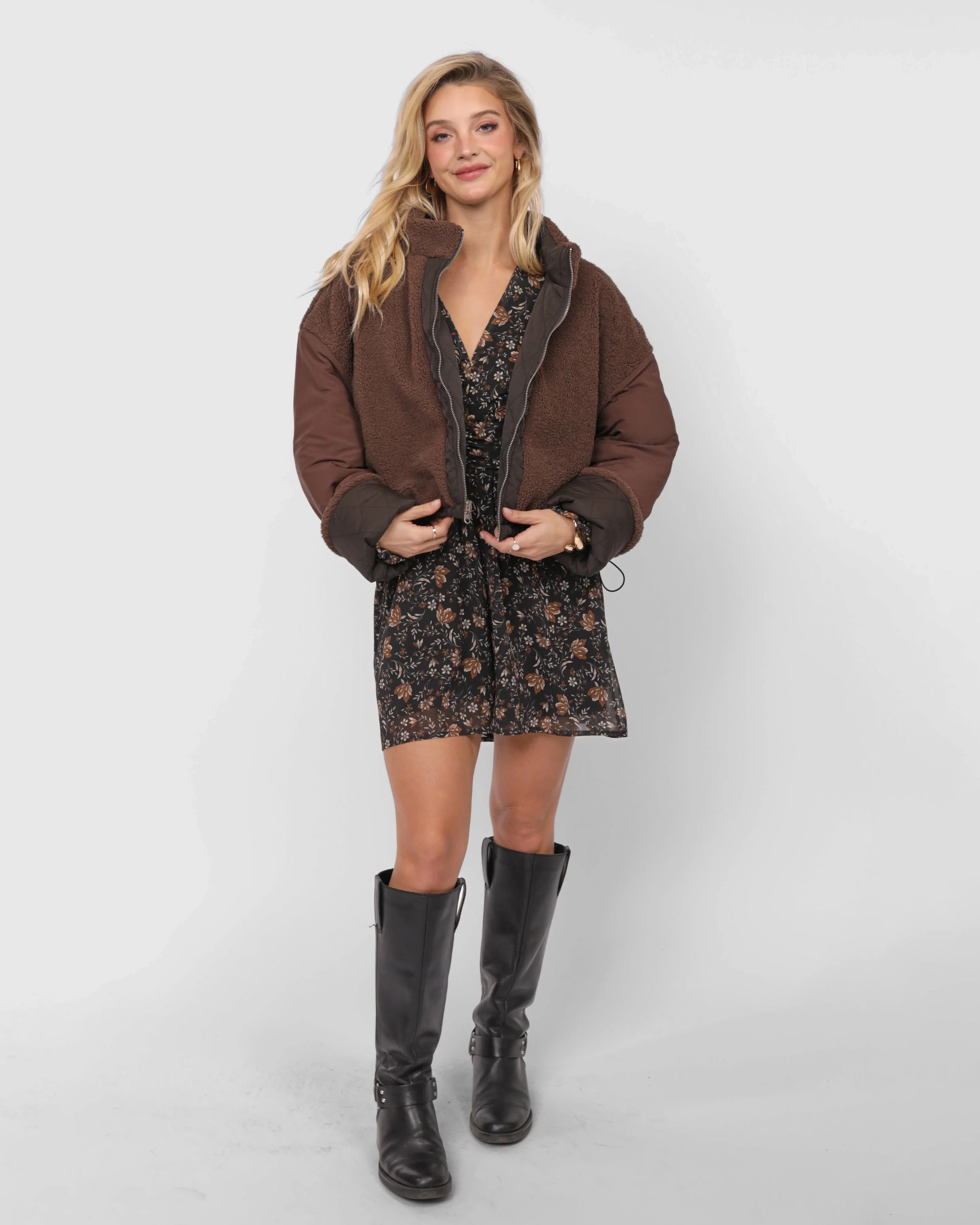 Woman wearing a brown teddy jacket over a floral dress 
