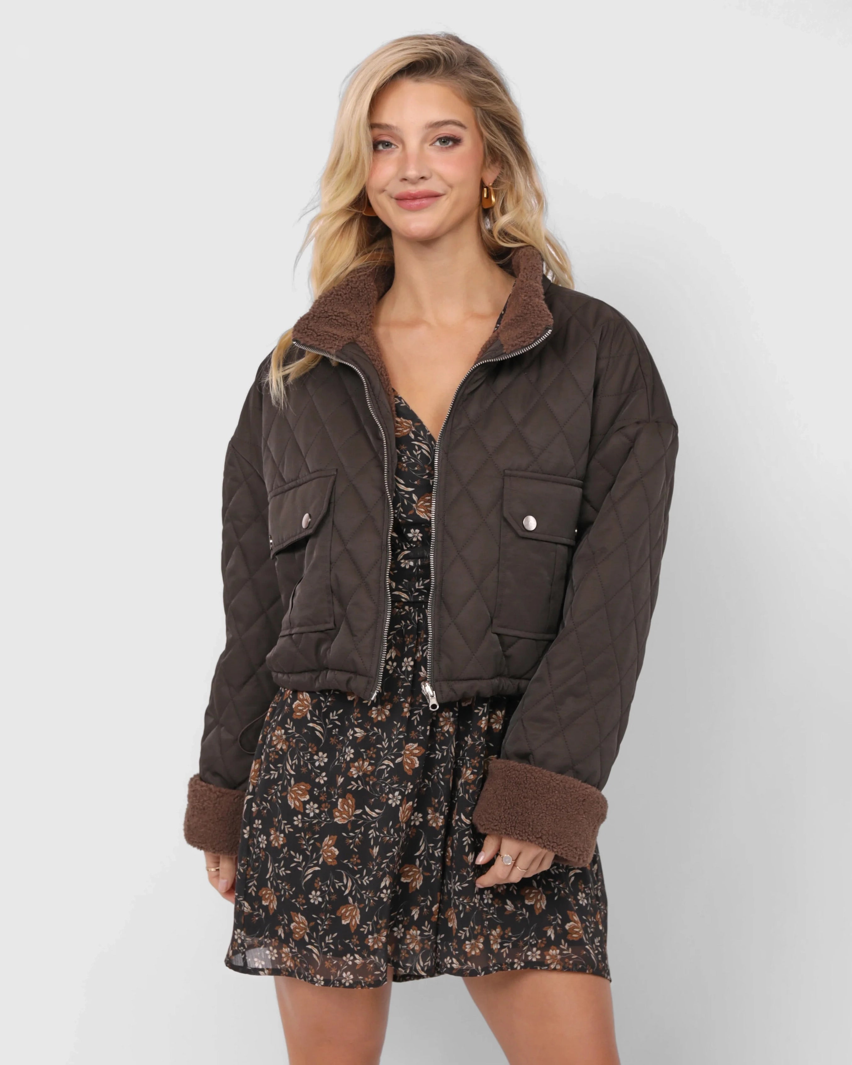 Woman wearing a brown quilted jacket over a floral dress 