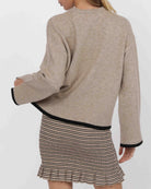 woman wearing a beige knit sweater with black piping