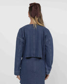 woman wearing a blue textured denim jacket and skirt set 