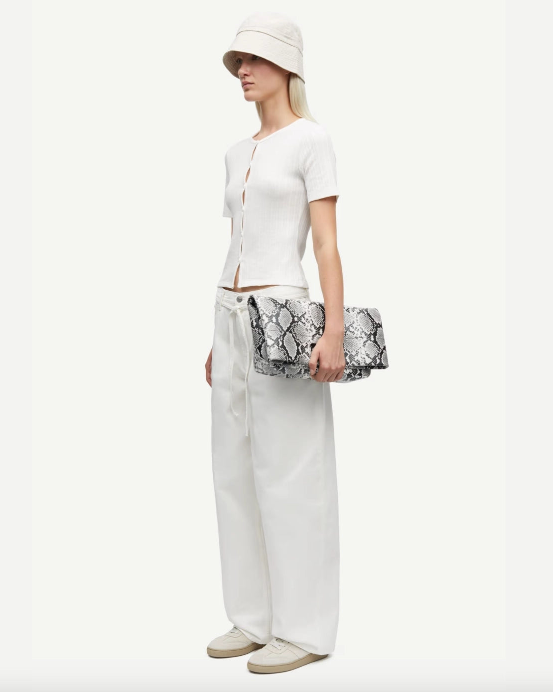 Woman wearing a white short-sleeve button down cardigan top and pants 