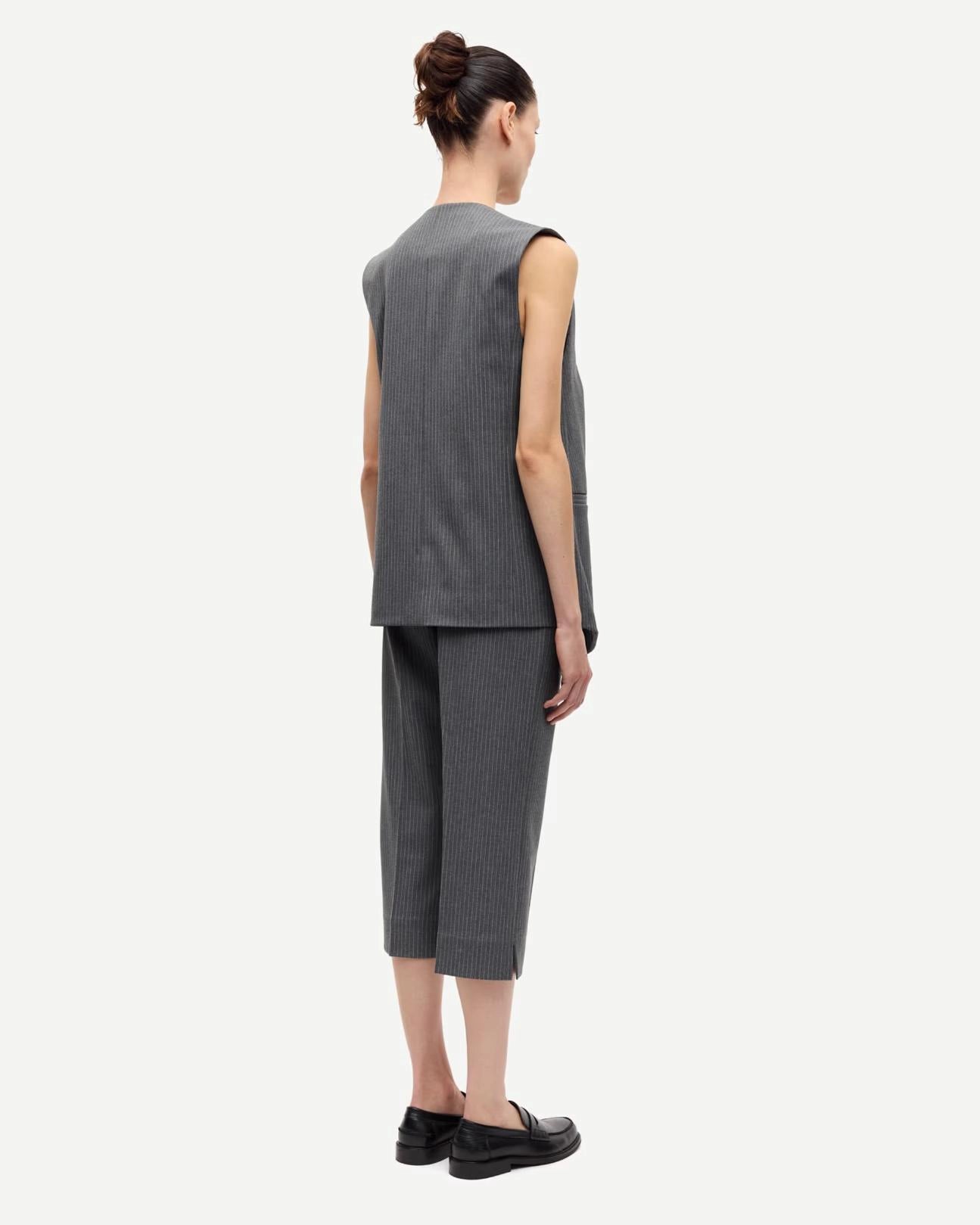 woman wearing a grey pinstriped vest 