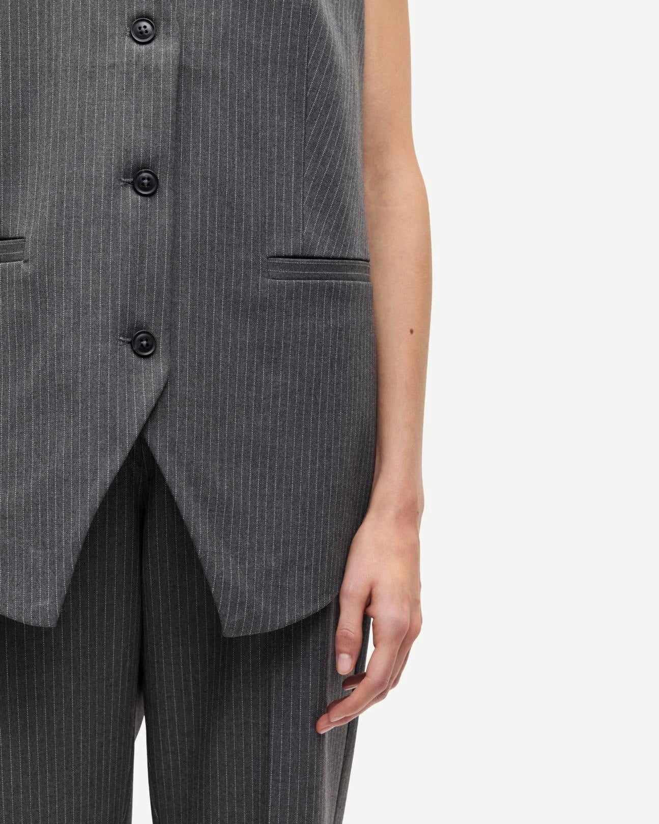 woman wearing a grey pinstriped vest 