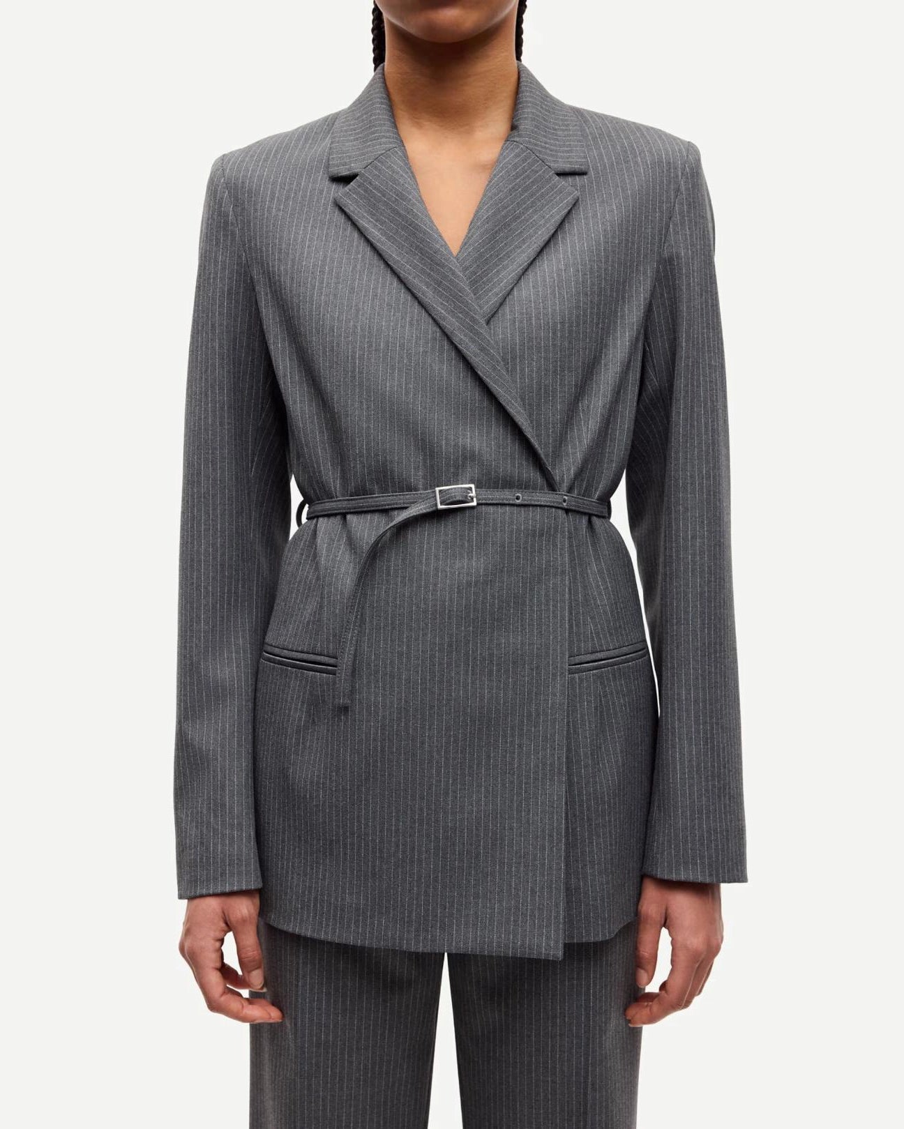 Woman wearing a gray pinstripe suit blazer with belt
