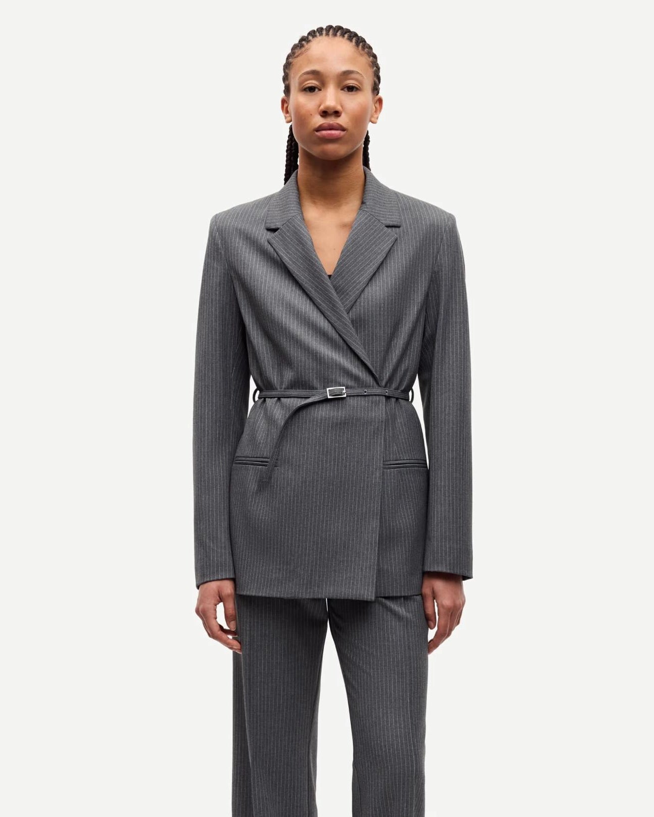 Woman wearing a gray pinstripe suit blazer with belt