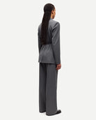 Woman wearing a gray pinstripe suit blazer with belt and matching trousers