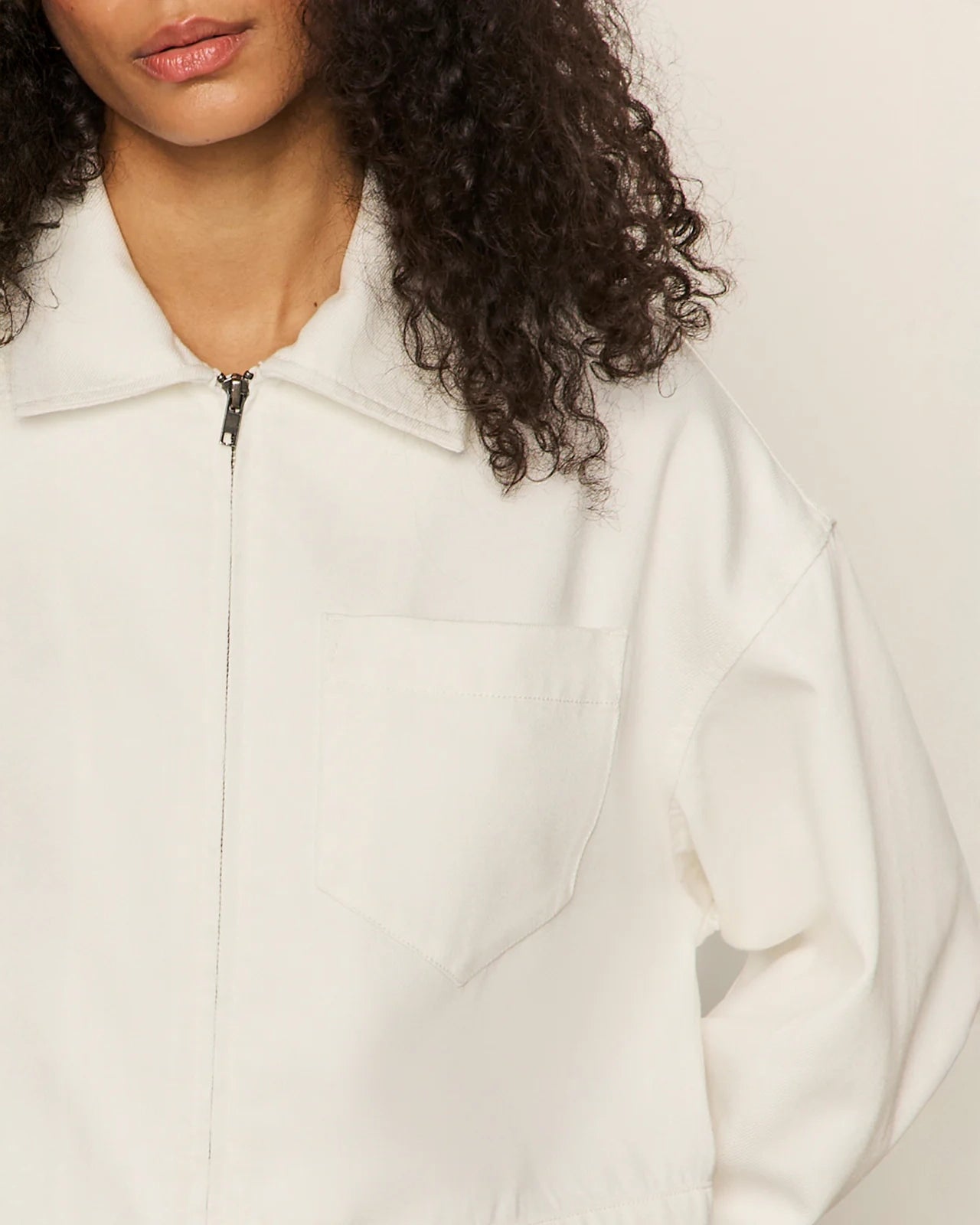 Close up of a woman wearing a white cropped zip jacket