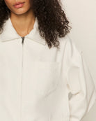 Close up of a woman wearing a white cropped zip jacket