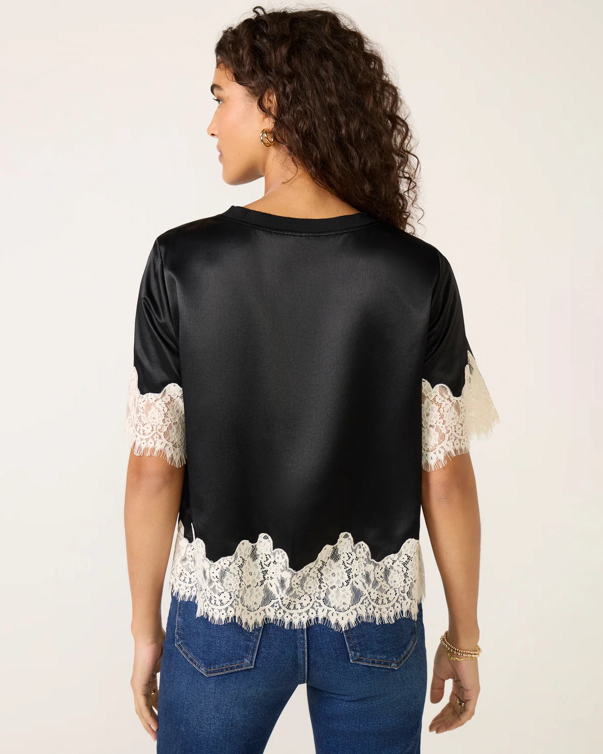 a woman weard a black short sleeve top with cream lace on the bottom and on the sleeves
