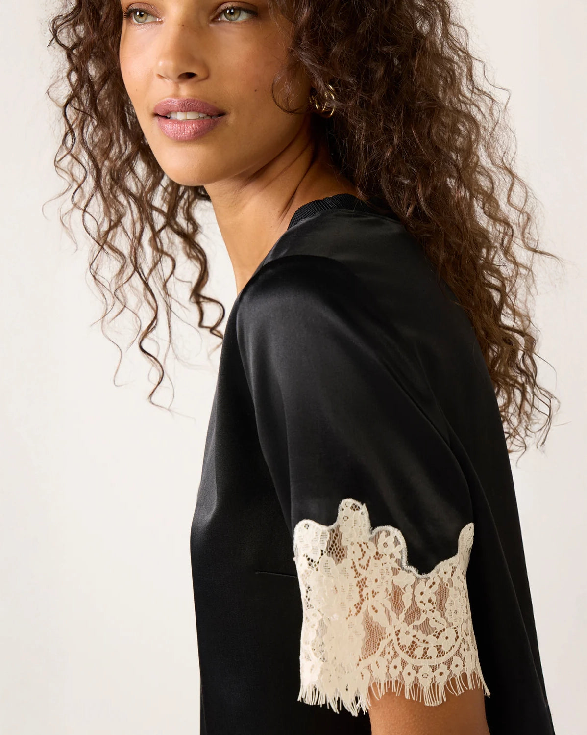 a woman weard a black short sleeve top with cream lace on the bottom and on the sleeves