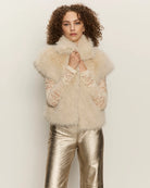 Woman wearing a faux fur short sleeve vest in blonde cream colour