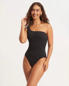 Woman wearing a black one-piece swimsuit with one shoulder design by Seafolly