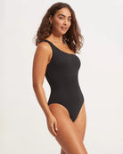 Woman wearing a black one-piece swimsuit with one shoulder design by Seafolly