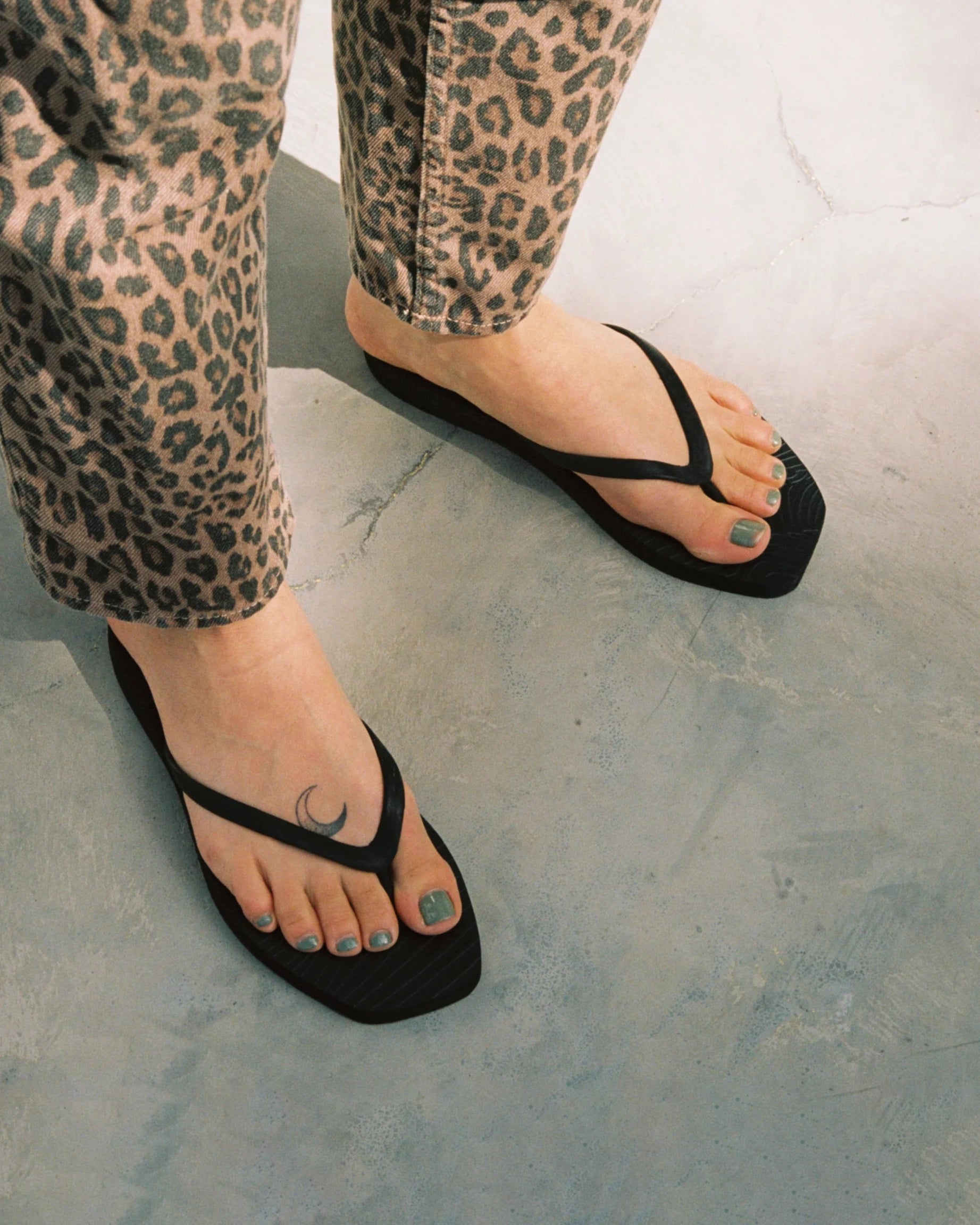 Black flip-flops worn with leopard print pants