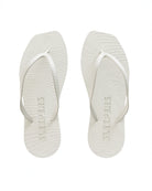 Pair of white flip-flop sandals by Sleepers with logo on the bottom