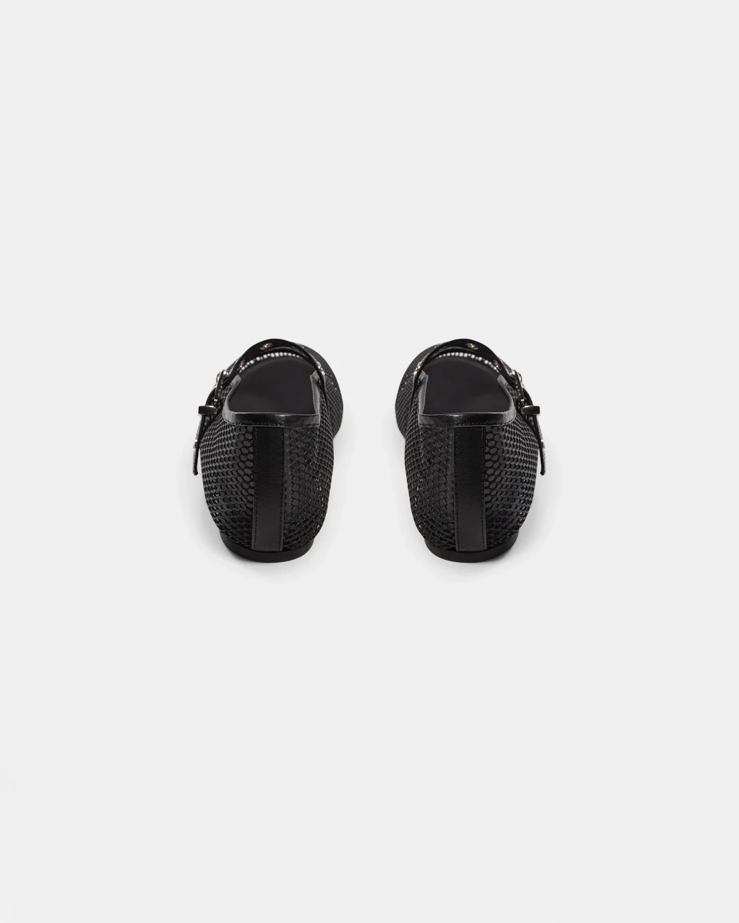 a black ballerina flat that is mesh and has a strap going across the foot with meal holes and a buckle