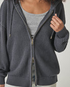 Woman wearing a netted gray zip up cardigan 