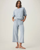 person wearing light blue grey terry pants  and matching sweater with drawstring and elastic waistband