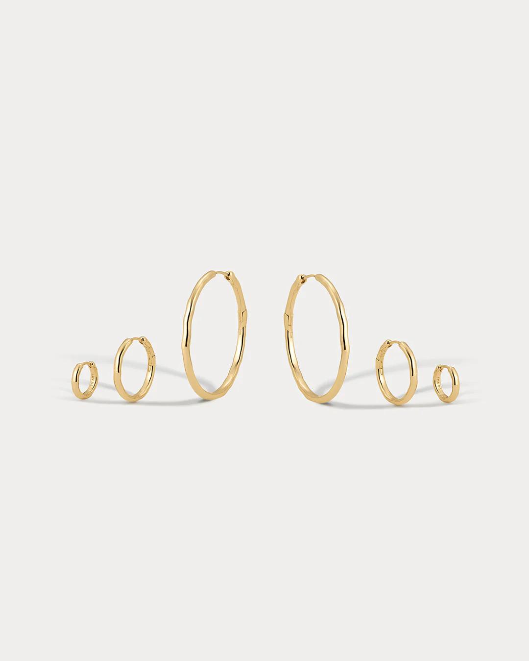 Set of gold hoop earrings on a light gray background
