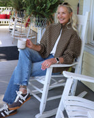 woman wearing a plaid jacket with jeans and sunglasses on a rocking chair