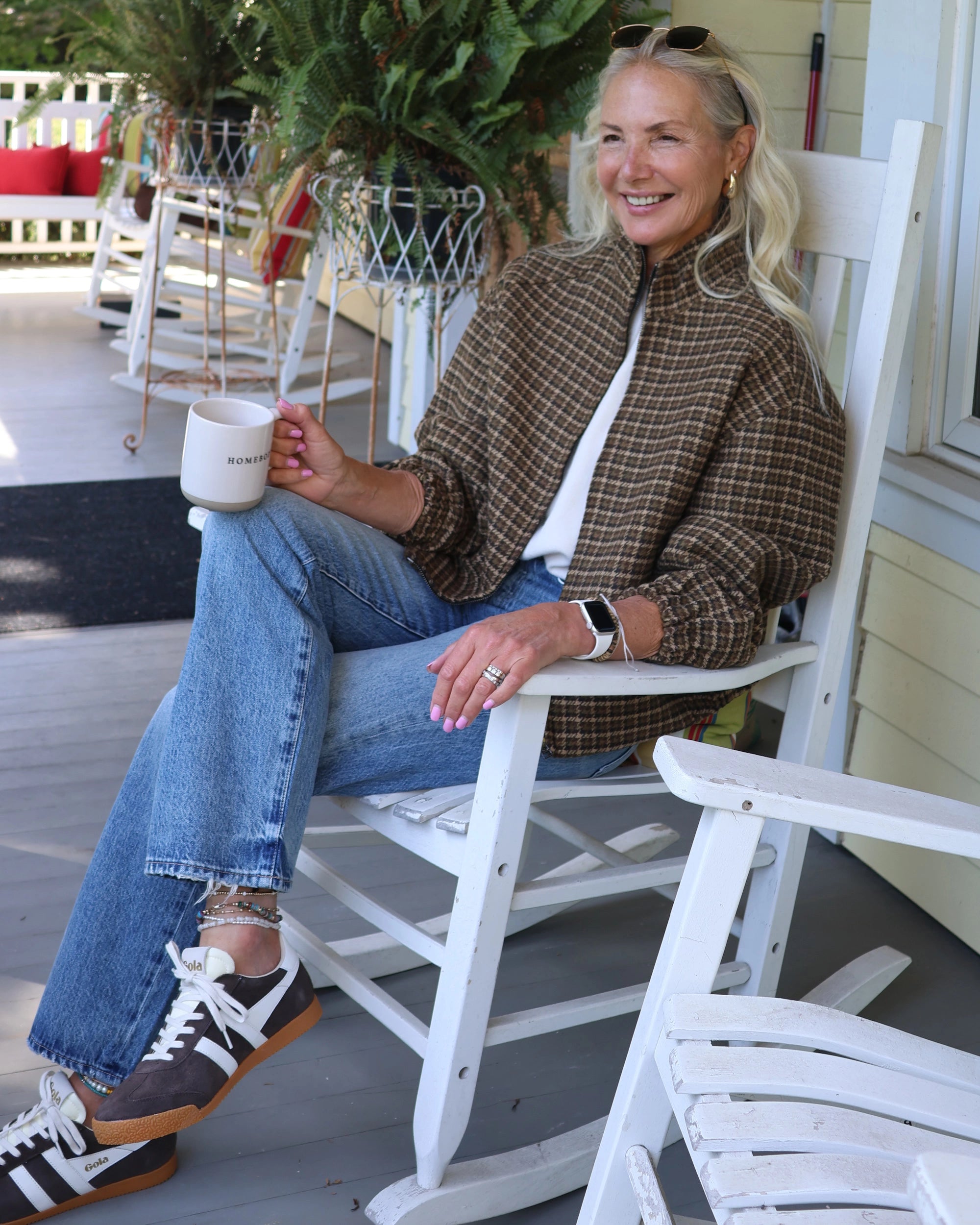woman wearing a plaid jacket with jeans and sunglasses on a rocking chair