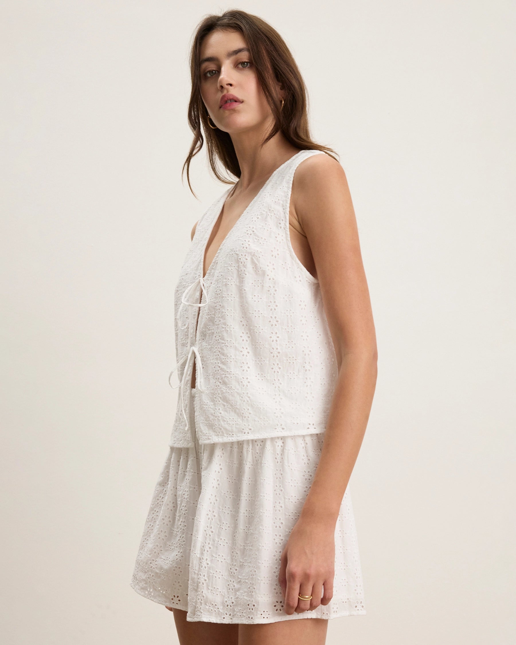 Woman wearing a white lace eyelet blouse with matching shorts