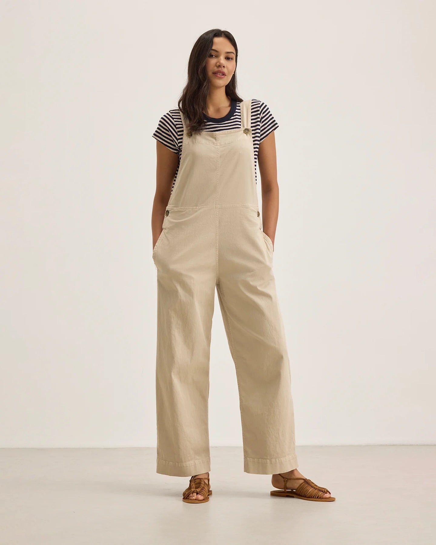 Woman wearing beige overalls with a striped shirt