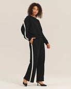 Woman wearing a black outfit with white stripes and matching trousers