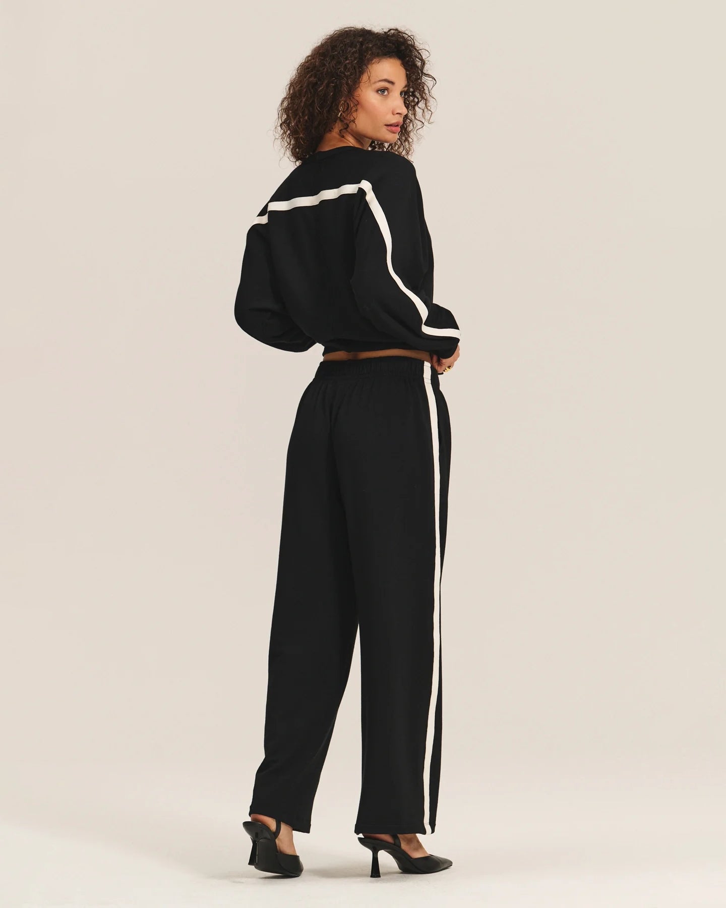 Woman wearing a black outfit with white stripes and matching trousers