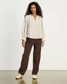 Woman wearing a patterned blouse and brown corduroy pants