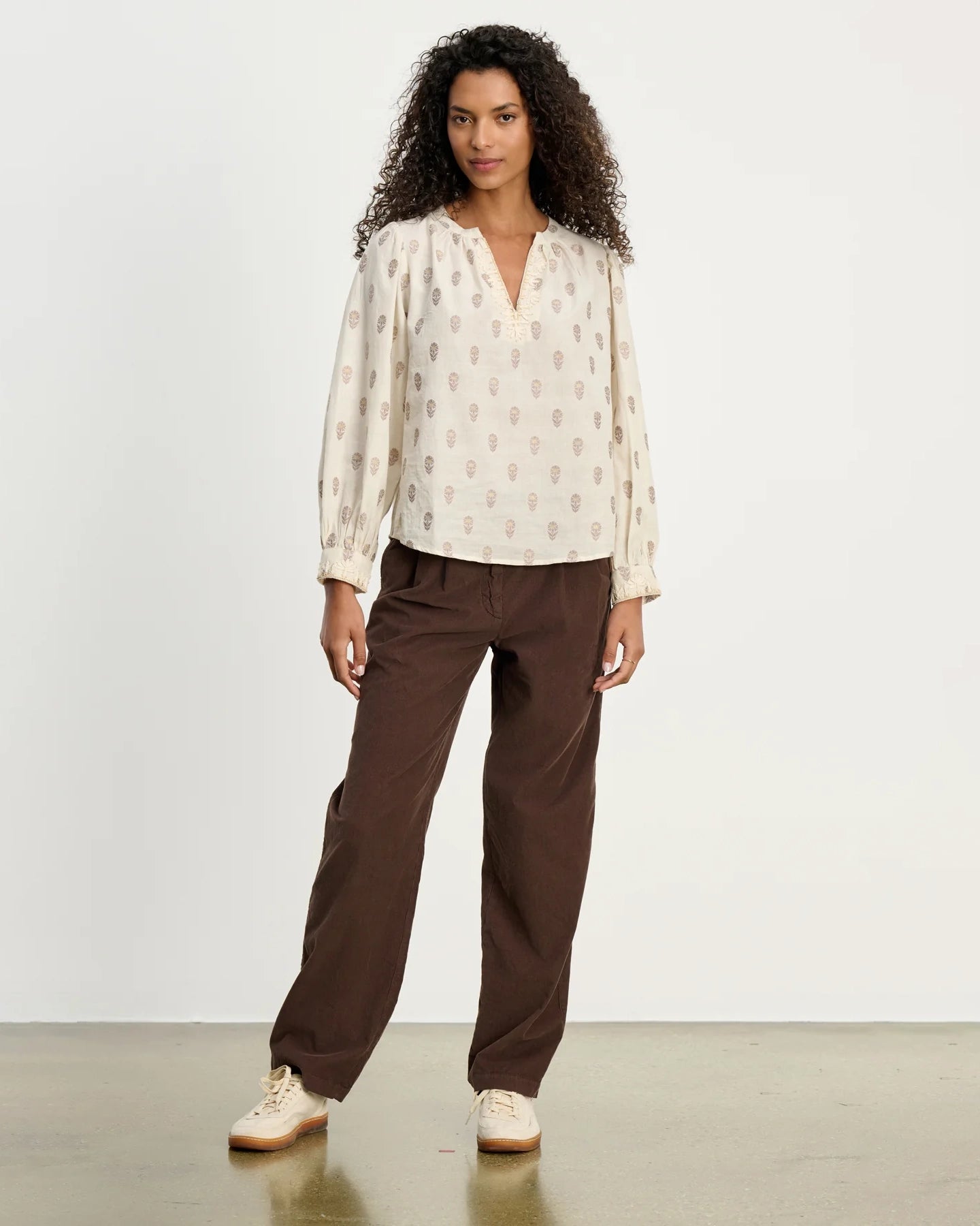 Woman wearing a patterned blouse and brown corduroy pants