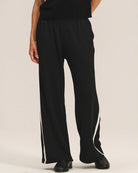 a woman wears a pair of fleece jogger pants in black with a cream stripe down the side