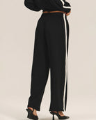 a woman wears a pair of fleece jogger pants in black with a cream stripe down the side