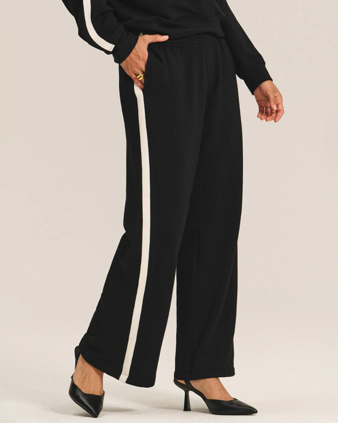 a woman wears a pair of fleece jogger pants in black with a cream stripe down the side