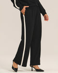 a woman wears a pair of fleece jogger pants in black with a cream stripe down the side