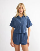 woman wearing blue terry cloth shorts and matching button down top
