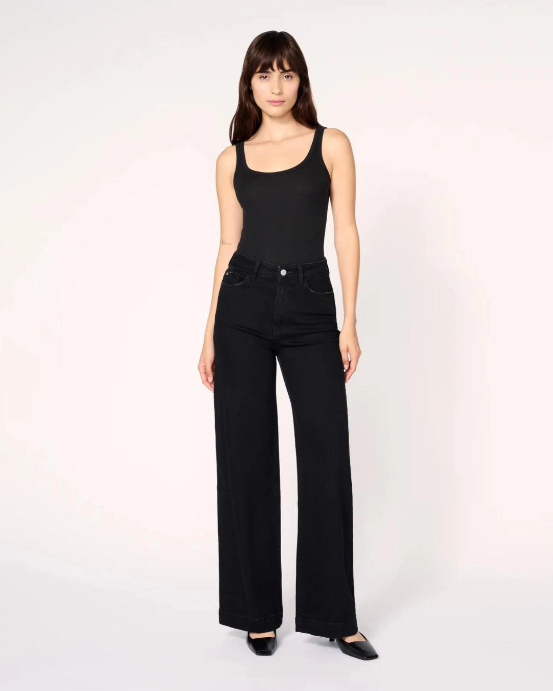 a woman wearing black wide-leg jeans with a thick cuff