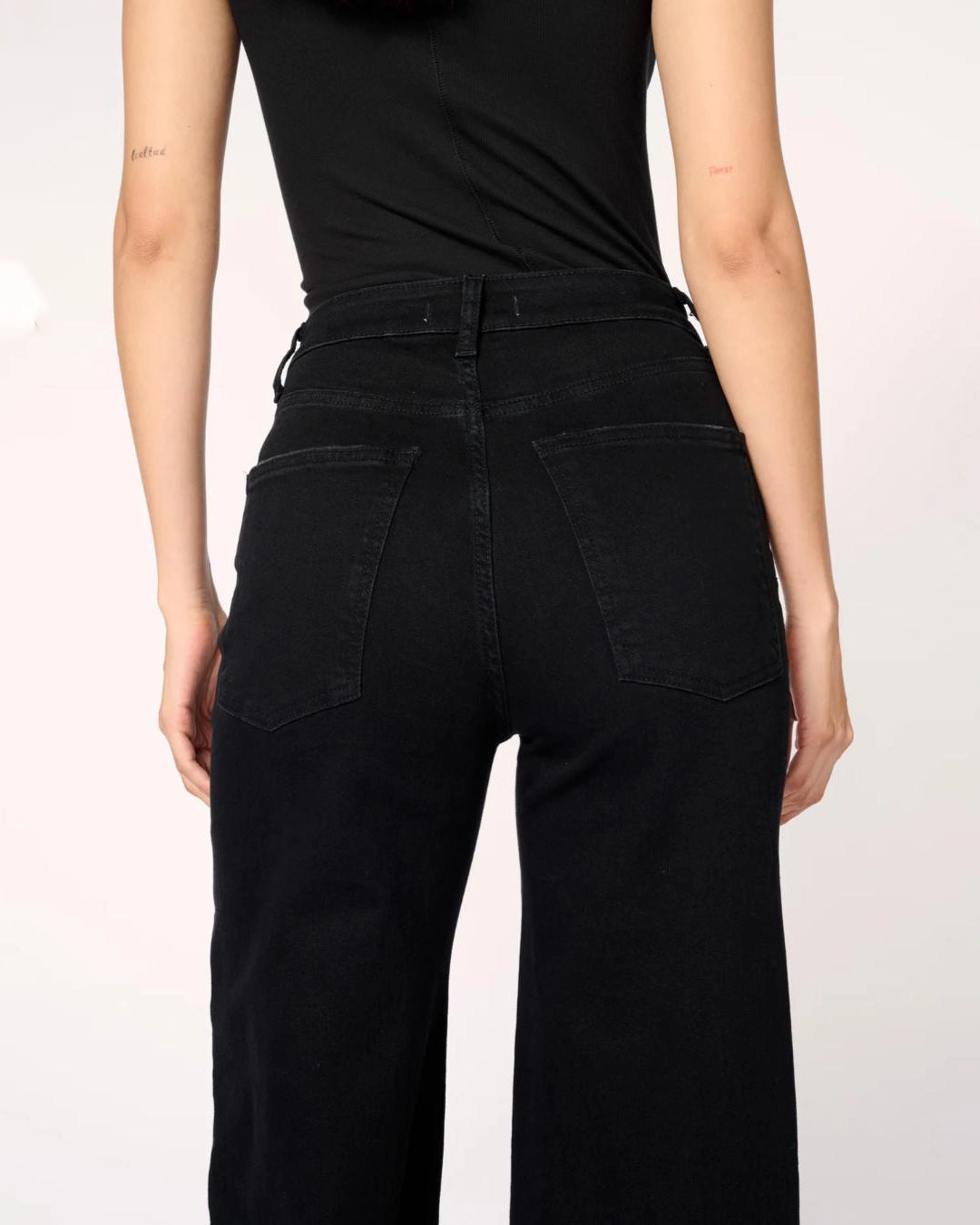 a woman wearing black wide-leg jeans with a thick cuff