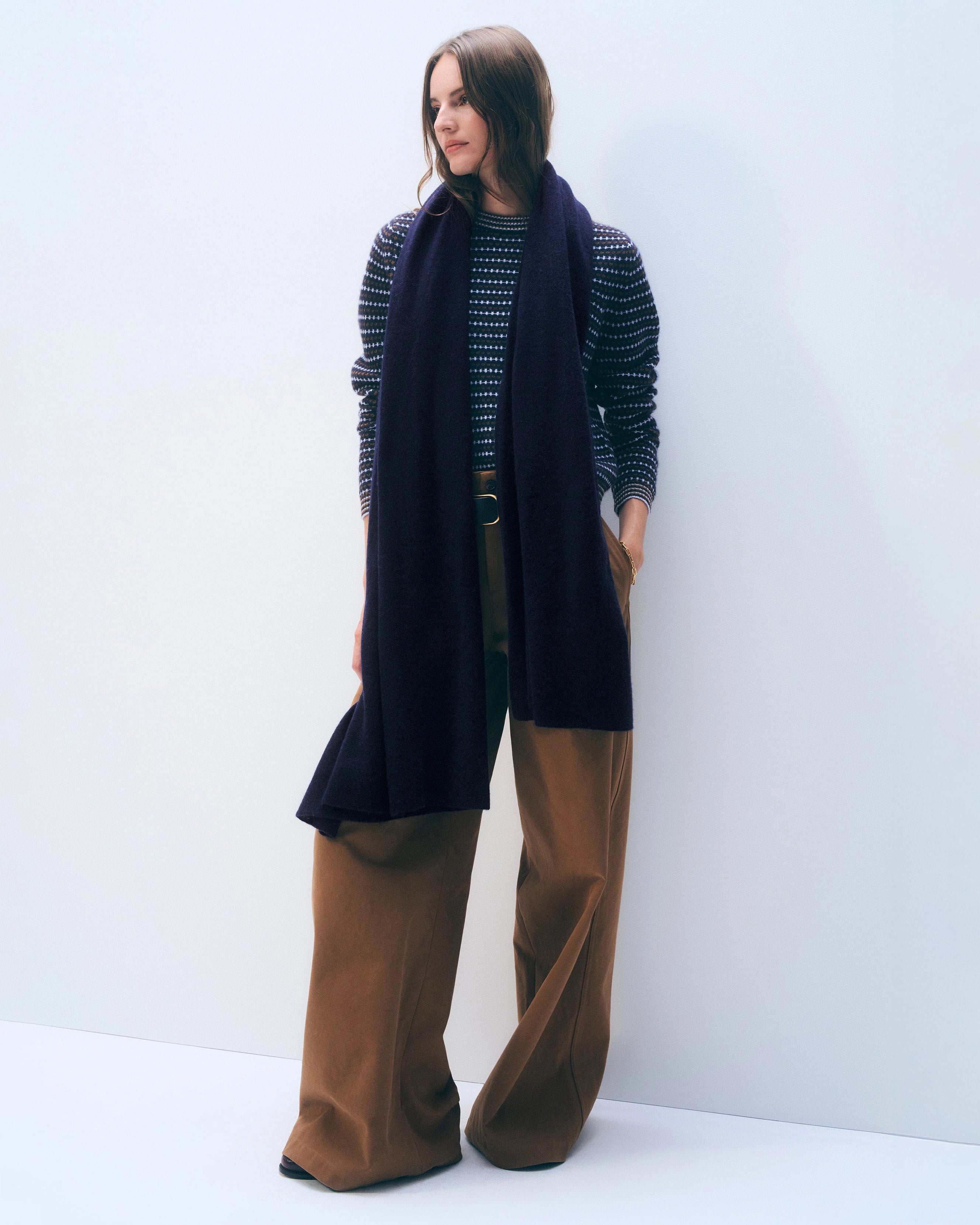 a woman wears a large cashmere travel wrap scarf in navy blue