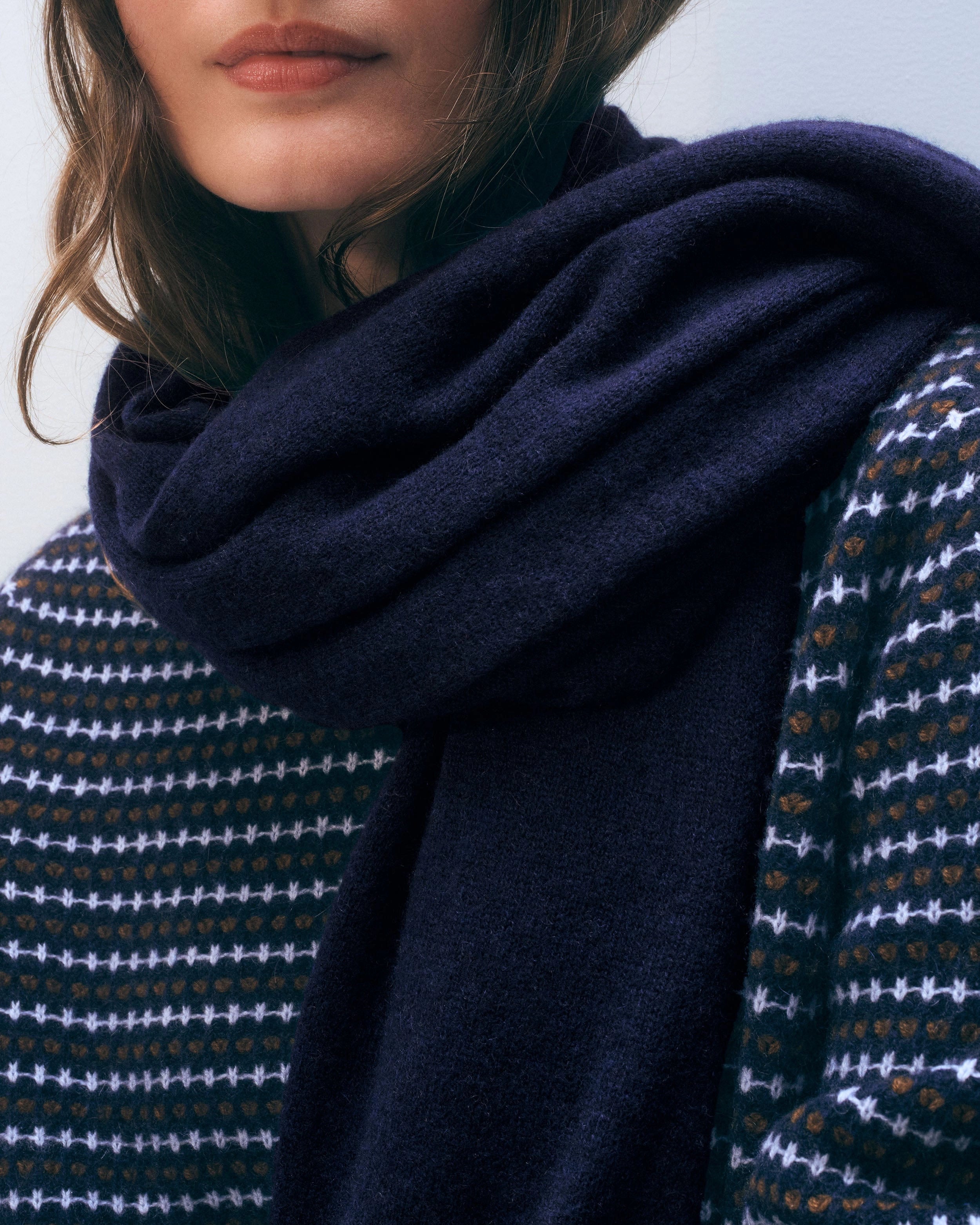 a woman wears a large cashmere travel wrap scarf in navy blue