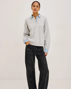 grey pullover sweatshirt with half buttons down and a blue striped collar