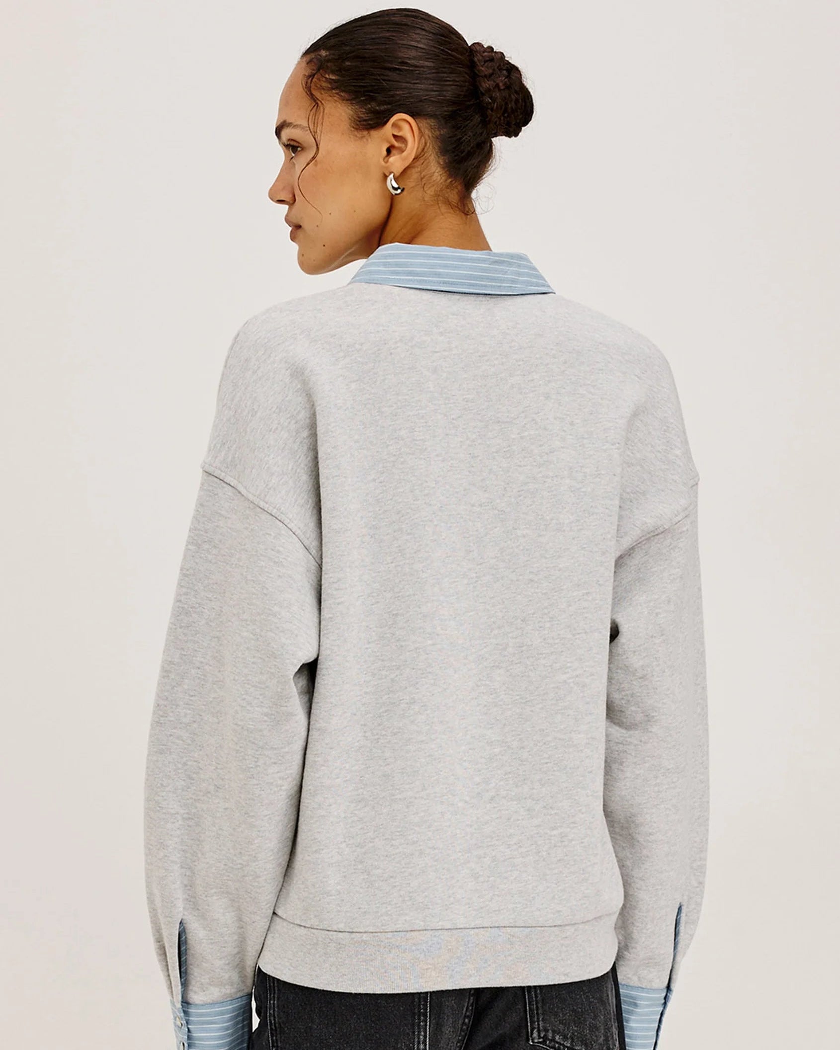 grey pullover sweatshirt with half buttons down and a blue striped collar