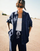 Woman wearing a blue denim button down jacket  with drawstring pants in the desert